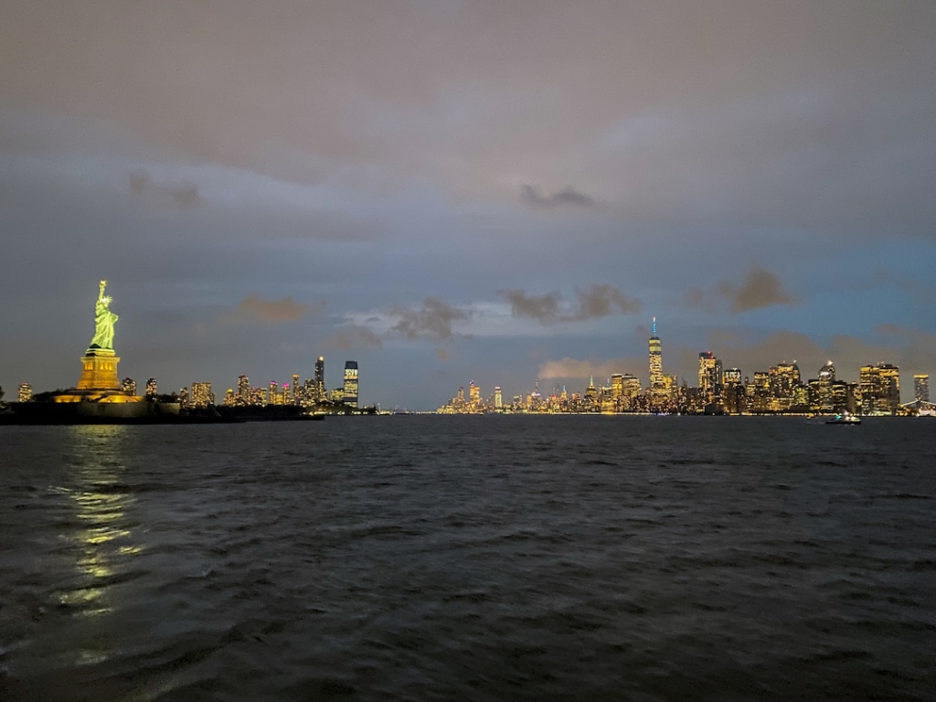 Skyline de Manhattan avec la Statue de la Liberté de nuit depuis un bateau de croisière