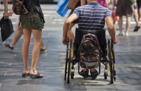 Personne en fauteuil roulant de dos à côté d'une personne debout