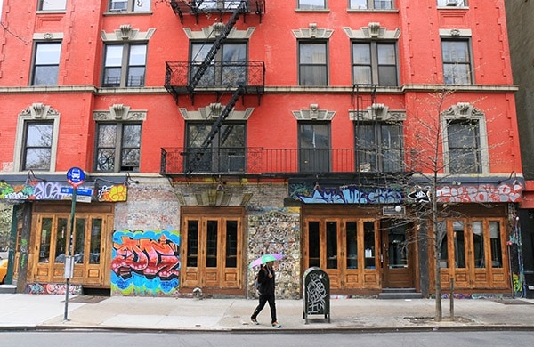 Bâtiment rogue avec escaliers en fonte visibles et graffiti autour des portes en bas