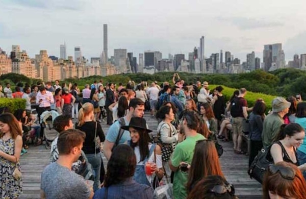 Extérieur d'un Rooftop rempli de personnes qui parlent, avec vu sur la Skyline de New York.
