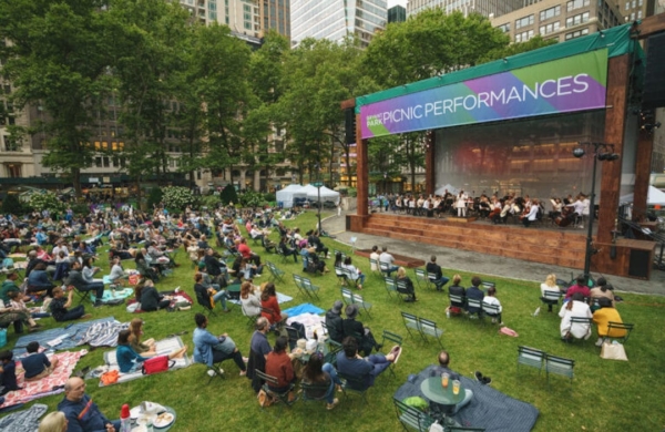 Personnes assises sur la pelouse de Bryant Park regardant un spectacle durant un Picnic Performances.